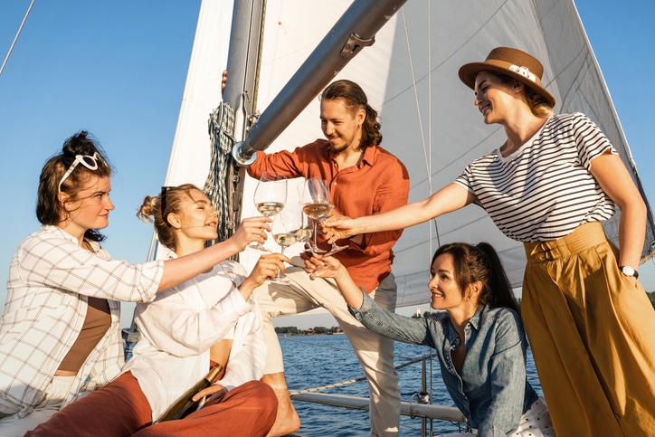 Group of happy friends drinking wine and relaxing on the sailboat for a brunch cruise in charleston sc